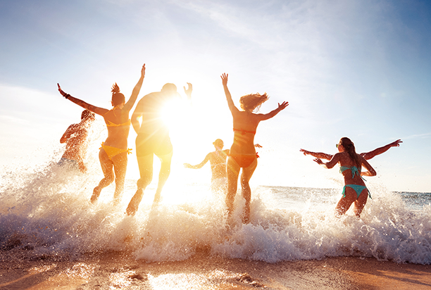 School leavers jumping in waves at the beach